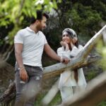 Young couple sharing a tender moment in a lush outdoor setting, expressing love and joy.