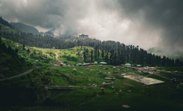 Dramatic view of lush green Malam Jabba landscape with hills and forest under overcast skies.