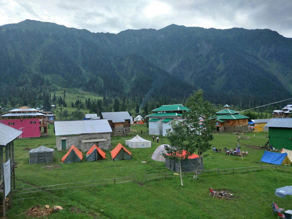 Explore the picturesque tents and cabins in Arang Kel against a stunning mountainous backdrop.