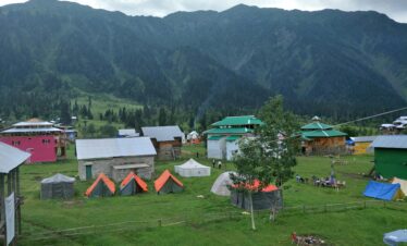 Explore the picturesque tents and cabins in Arang Kel against a stunning mountainous backdrop.
