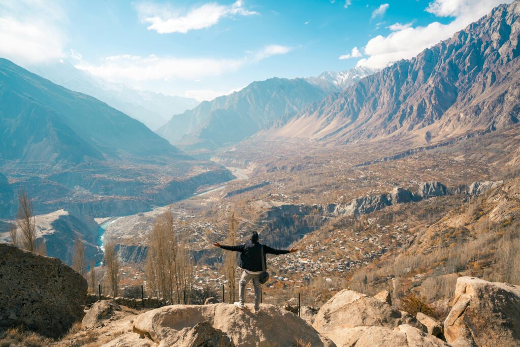A traveler enjoying a breathtaking view of Hunza Valley, Karakoram Mountains, Pakistan.