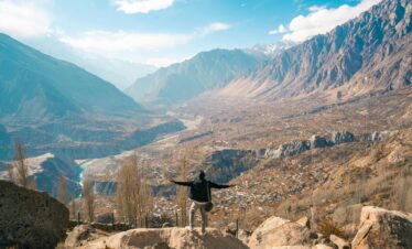 A traveler enjoying a breathtaking view of Hunza Valley, Karakoram Mountains, Pakistan.