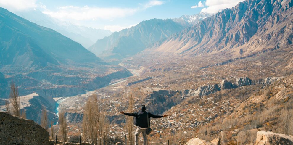 A traveler enjoying a breathtaking view of Hunza Valley, Karakoram Mountains, Pakistan.
