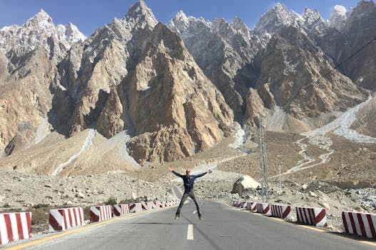 Person jumping on a road in Hunza Nagar with stunning mountain views.