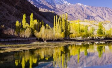 Stunning autumn scenery with vibrant trees reflected in Phander Lake, Pakistan.