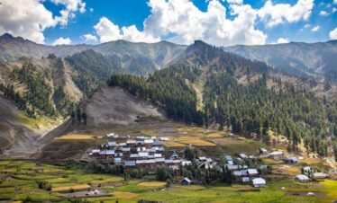 Panoramic view of Gurez village in Kashmir, surrounded by lush mountains and fields.
